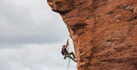 man in black shorts climbing brown rock formation during daytime