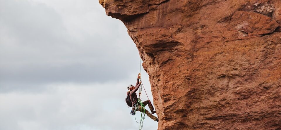 man in black shorts climbing brown rock formation during daytime